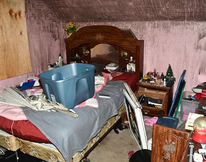 A disorganized bedroom with a large wooden headboard in the house where a stepson was held captive. A disorganized bedroom with a large wooden headboard in the house where a stepson was held captive.