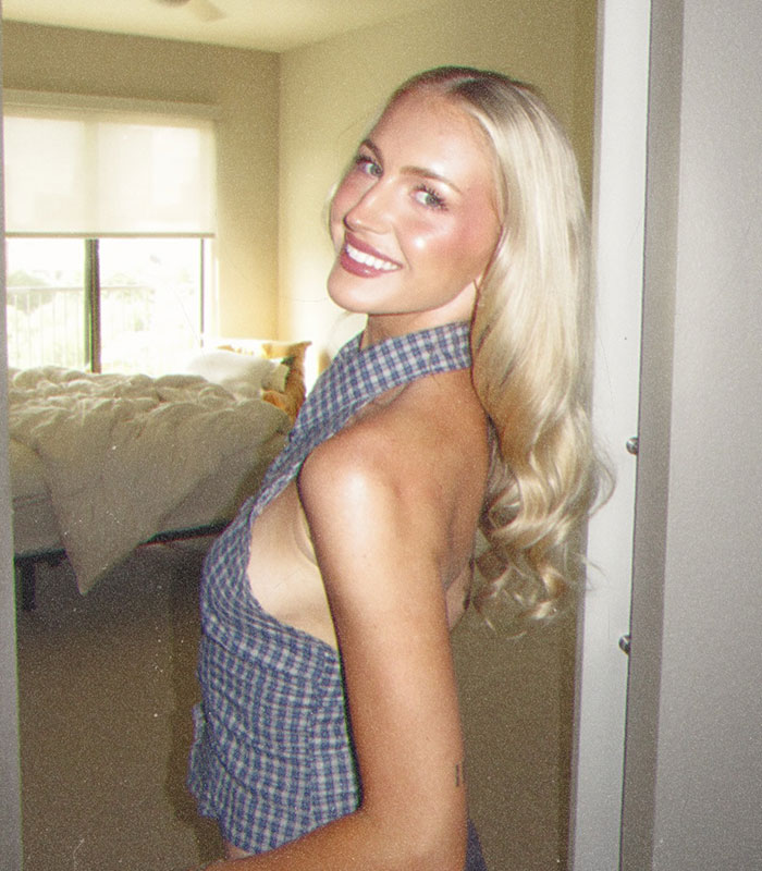 A smiling blonde bystander posing in her room after a Karen encounter.
