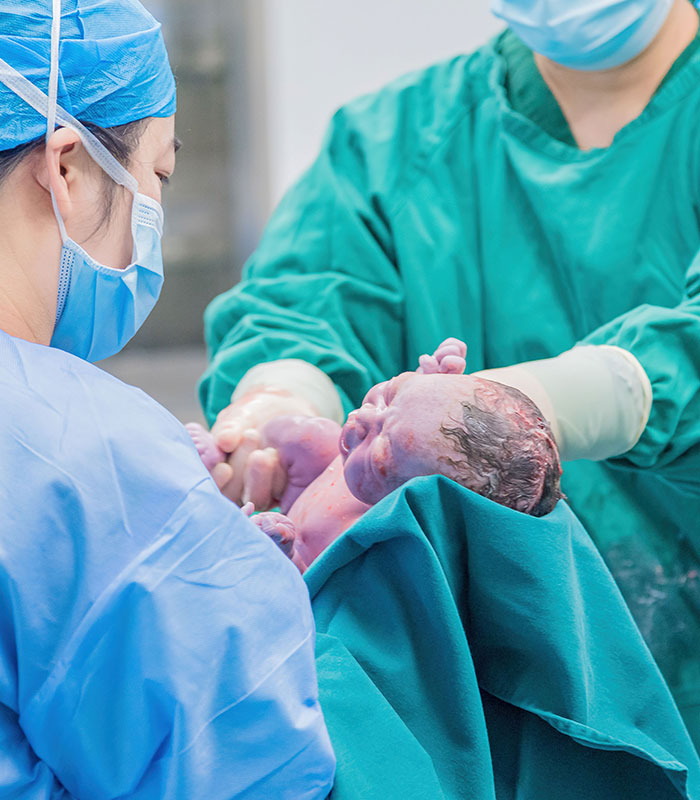 Healthcare professionals assisting birth of baby symbolizing star athlete's wife delivery
