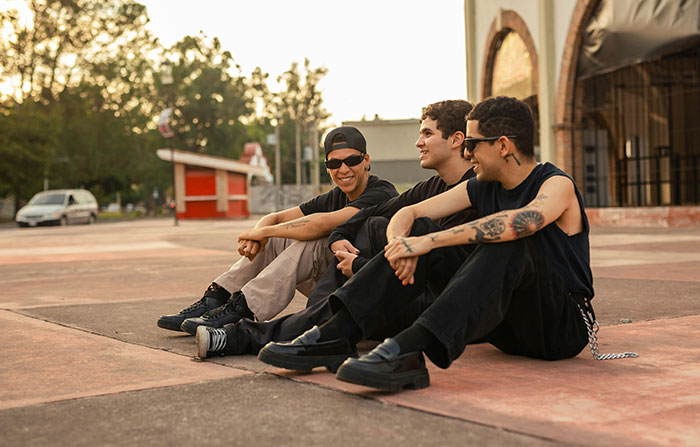 Group of young men sitting outside, casually chatting and laughing Group of young men sitting outside, casually chatting and laughing