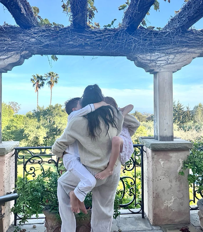A parent embraces children on a balcony, symbolizing Prince Harry's kids and the privacy concerns around their schooling.