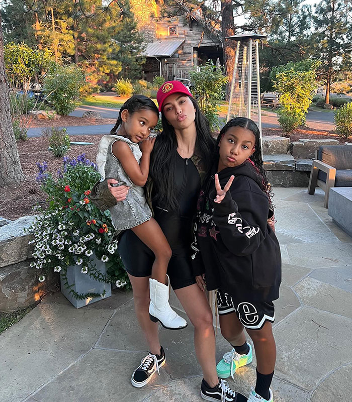 Kim Kardashian with daughters North West at 13 and Chicago, posing outdoors amidst parenting controversy.