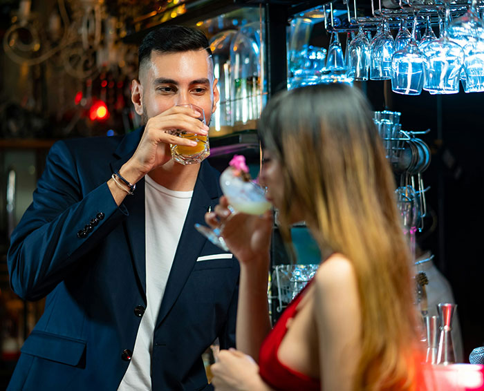 A man and a woman having drinks at a bar, learning how to avoid dating mistakes on a first date. A man and a woman having drinks at a bar, learning how to avoid dating mistakes on a first date.