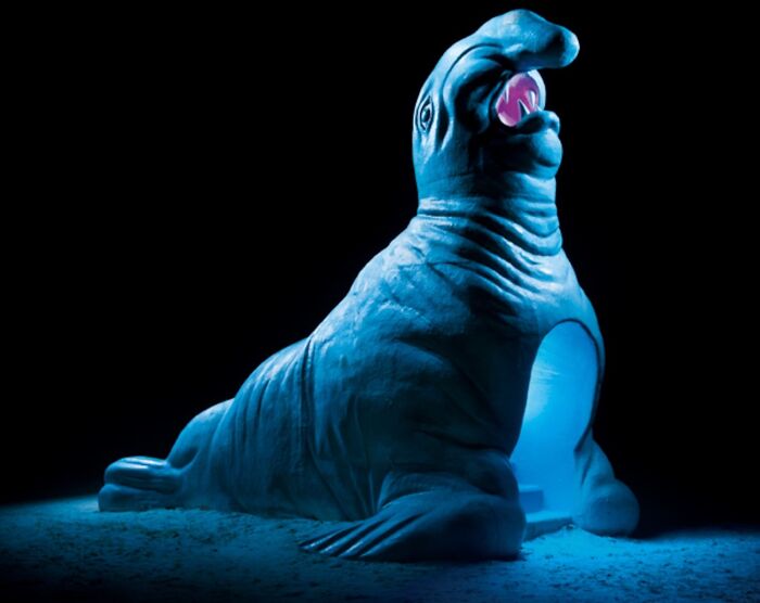 A large, blue-lit seal-shaped Japanese playground sculpture at night, captured by Fujio Kito, looking like another world scene.