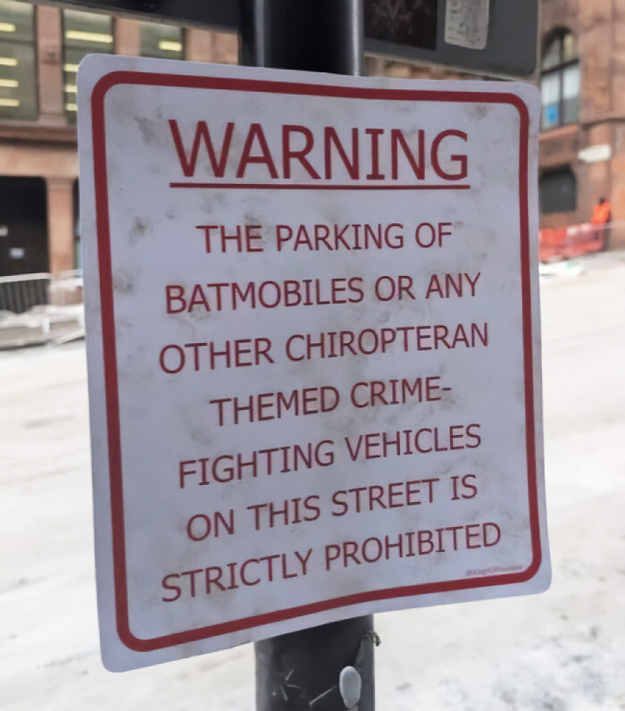 A funny sign warning against parking Batmobiles or other crime-fighting vehicles on the street.