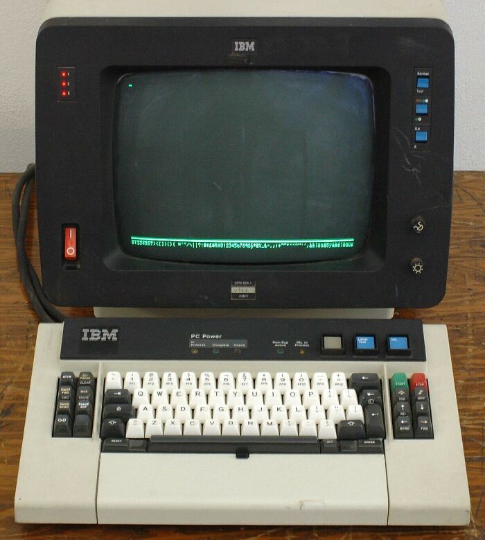 An old IBM personal computer with a green screen monitor and a large keyboard, highlighting 80s retro tech.