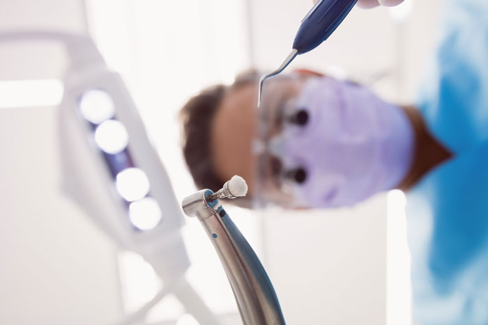 A low-angle view of a dentist holding tools, signifying the headaches that relationships can bring.