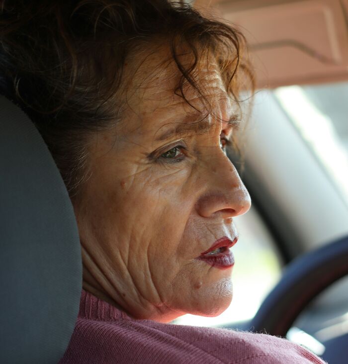 Elderly woman in a car, looking away, reflecting on going no contact with a parent.