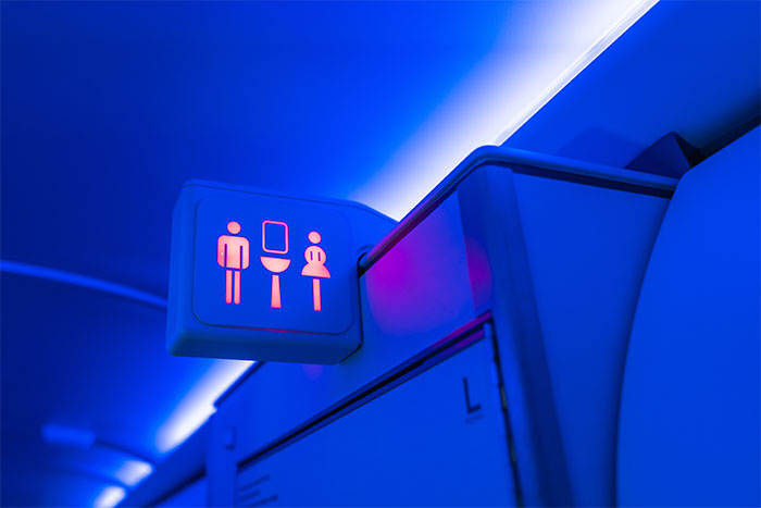 A glowing restroom sign on an airplane, highlighting passenger etiquette that makes flight attendants roll their eyes.