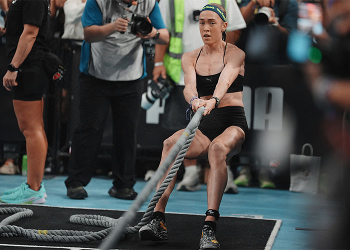 HYROX athlete intensely pulling a rope during a race, prior to the consequence for soiling herself.
