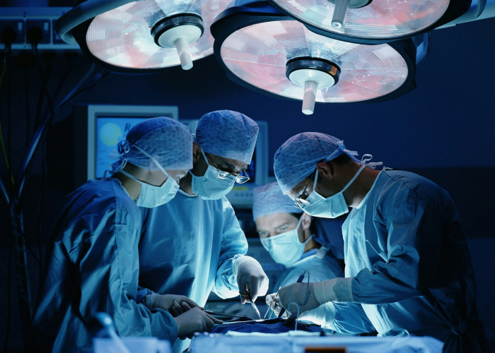 Doctors performing surgery under bright lights in hospital operating room