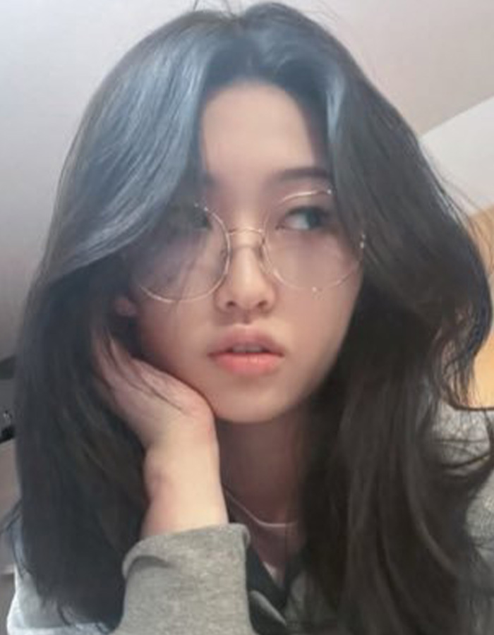 Portrait of young woman with glasses resting head on hand looking sideways indoors