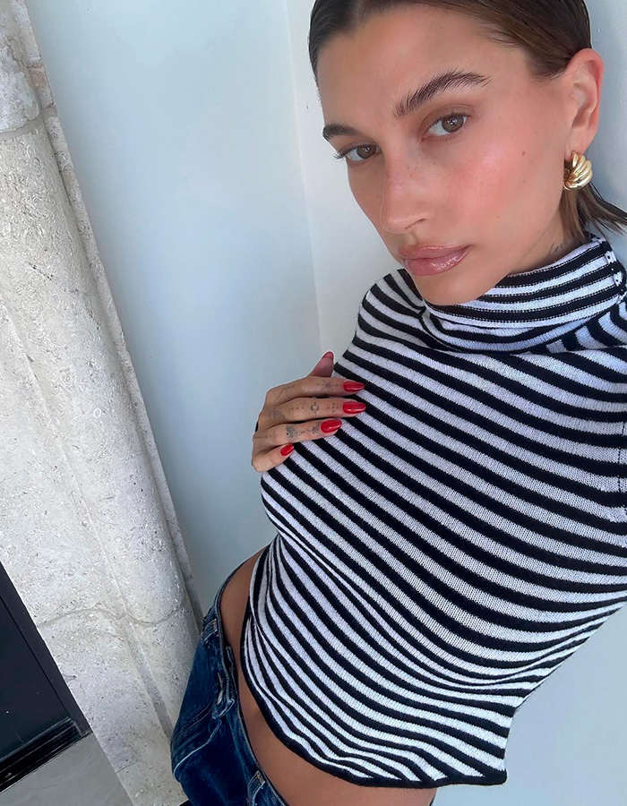 Woman posing with bold Gen Z pose wearing striped top Woman posing with bold Gen Z pose wearing striped top