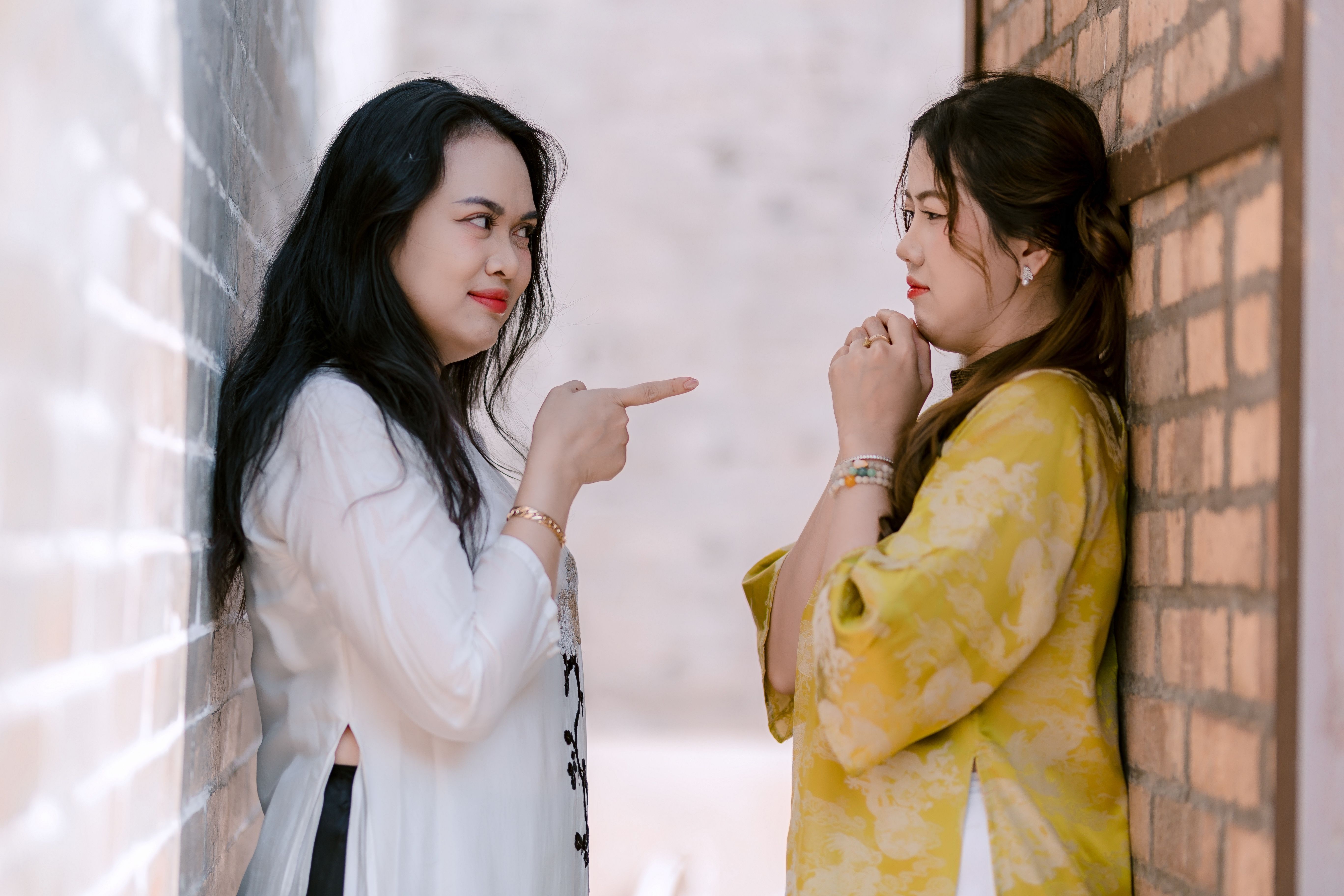 Two women arguing intensely with brick walls behind them