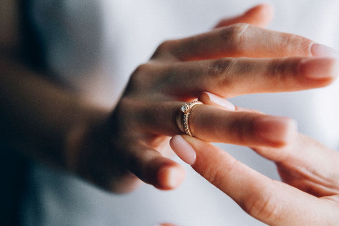 Close-up of hand removing engagement ring, symbolizing broken engagement