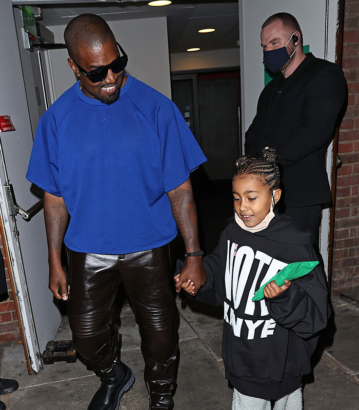 Kanye West and daughter North West at 13 holding hands, sparking parenting controversy.