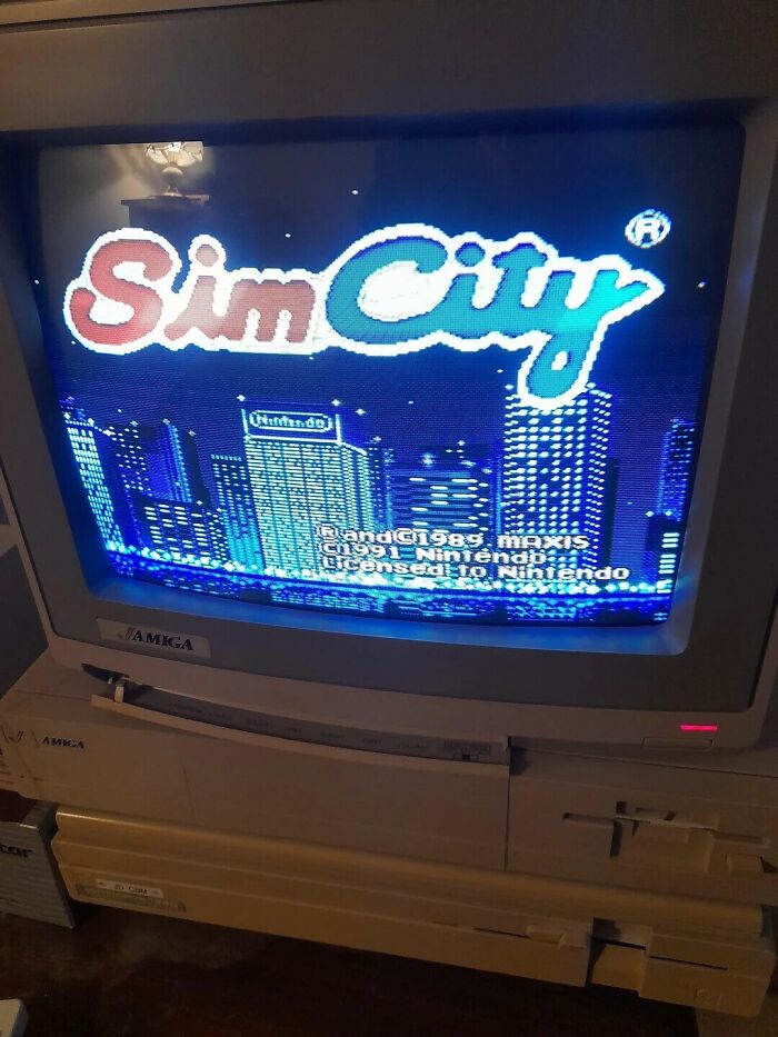A CRT monitor displaying the SimCity title screen on an Amiga computer, showcasing '80s retro tech gaming.