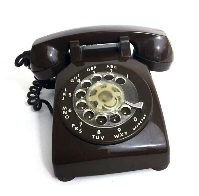 A classic brown rotary phone on a white background, representing 80s retro tech.