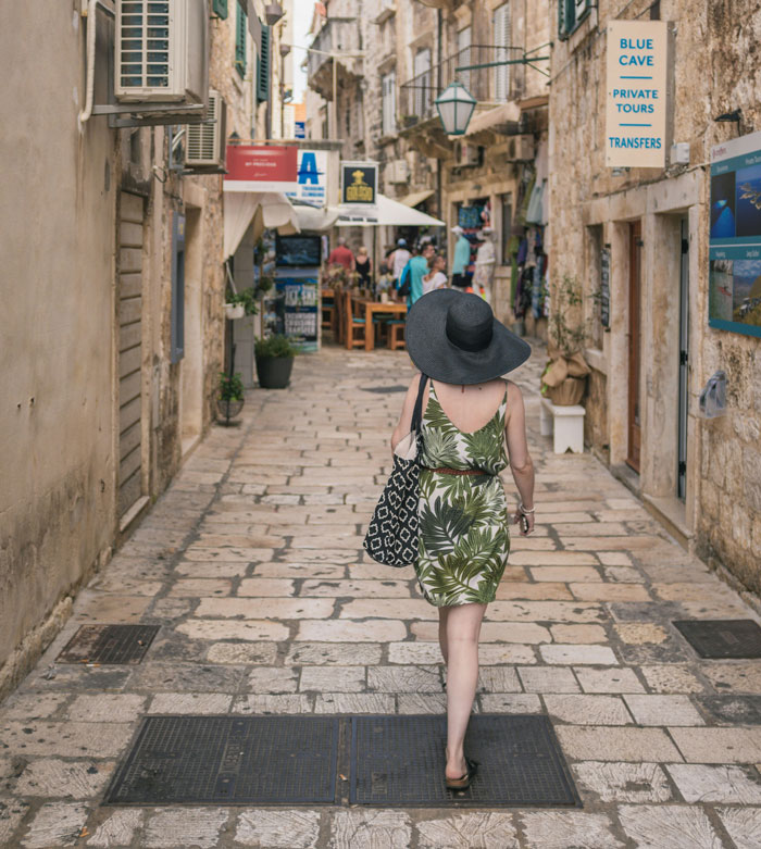 Woman in a wide-brimmed hat walking down a narrow street, symbolizing freedom before relationships turn into headaches.