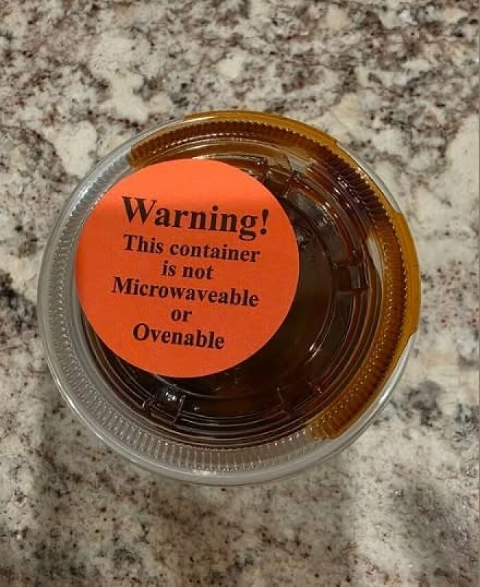 A funny warning sign on a small container of sauce that reads, This container is not Microwaveable or Ovenable.
