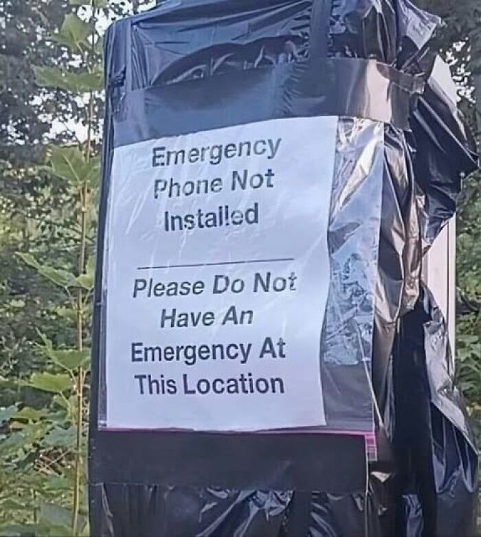 A silly sign on a black trash bag stating, Emergency Phone Not Installed. Please Do Not Have An Emergency.