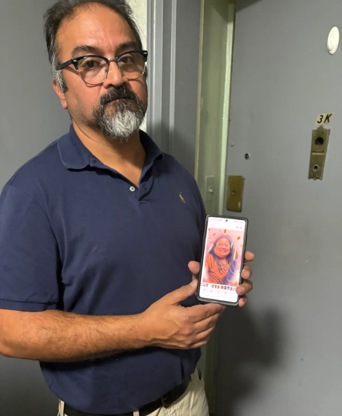 Man holding a phone displaying a picture of the Times Square victim, a Bank of America VP. Man holding a phone displaying a picture of the Times Square victim, a Bank of America VP.