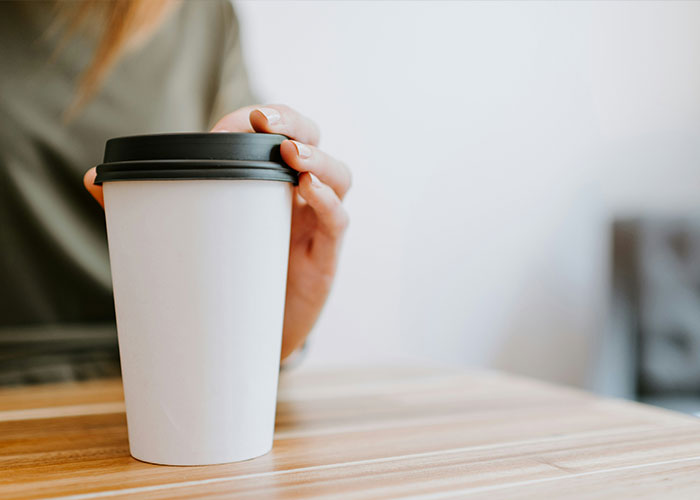 A hand reaching for a white coffee cup, representing the coffee at the center of a student's suspension.