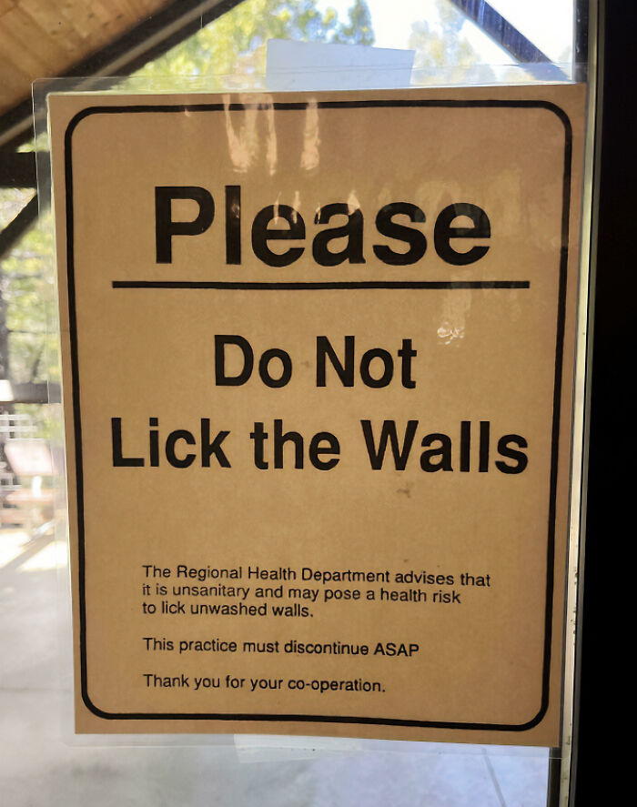 A chaotic sign spotted in the wild on a glass door, instructing Please Do Not Lick the Walls.