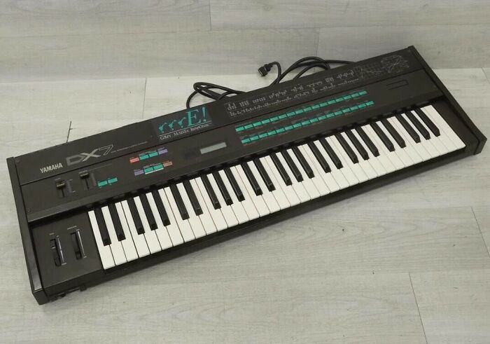 A classic Yamaha DX7 synthesizer, an iconic piece of retro tech from the 80s, displayed on a light surface.
