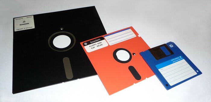 Three floppy disks of varying sizes (8-inch, 5.25-inch, and 3.5-inch), classic '80s retro tech storage.