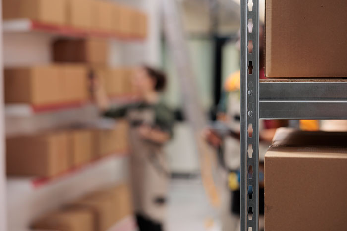A worker in a warehouse surrounded by boxes on shelves, contemplating 'I'm done' with their task.