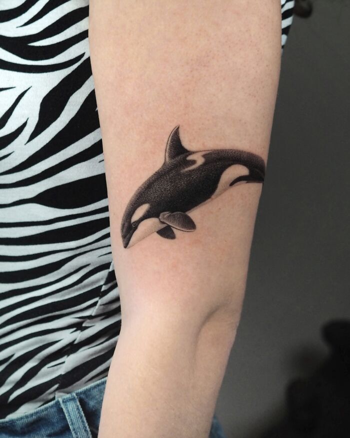 Black ink orca whale tattoo on arm