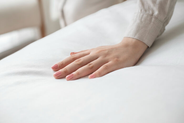 A hand resting gently on a soft white mattress, symbolizing comfort from ridiculous arguments.