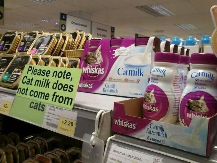 A silly funny sign in a store aisle clarifies that cat milk does not come from cats, next to cat milk products.