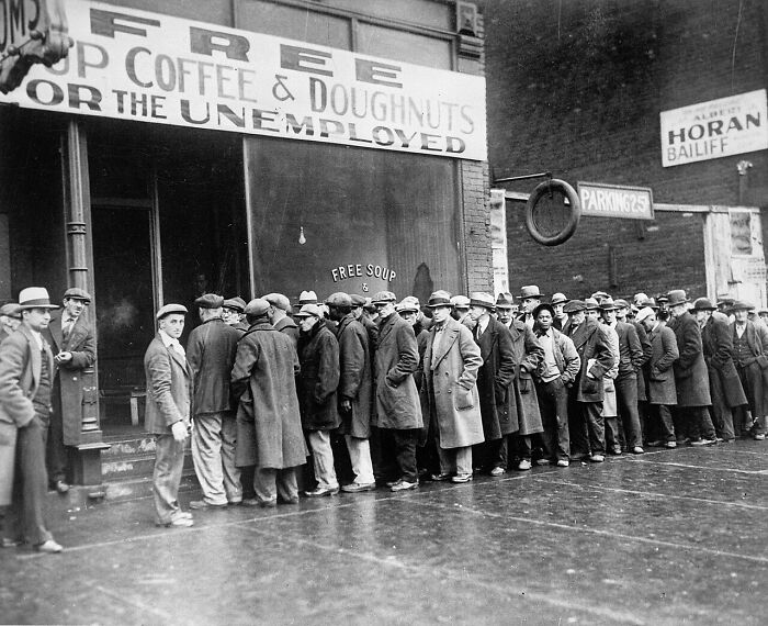 A long line of men during the Great Depression waiting for free soup, illustrating societal problems.