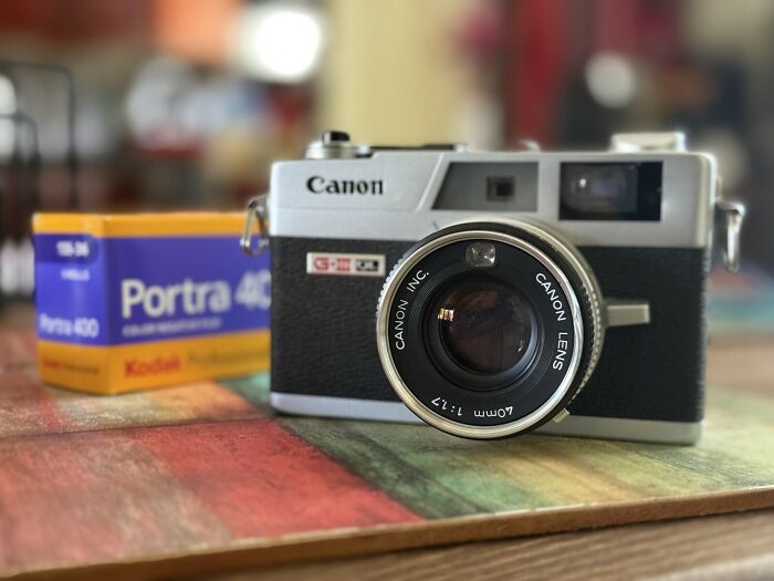 A vintage Canon camera with a roll of Portra 400 film in the background, a perfect example of retro tech.