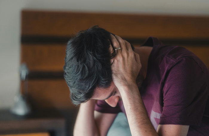 A man holding his head in distress, representing the headaches and struggles men face in relationships.