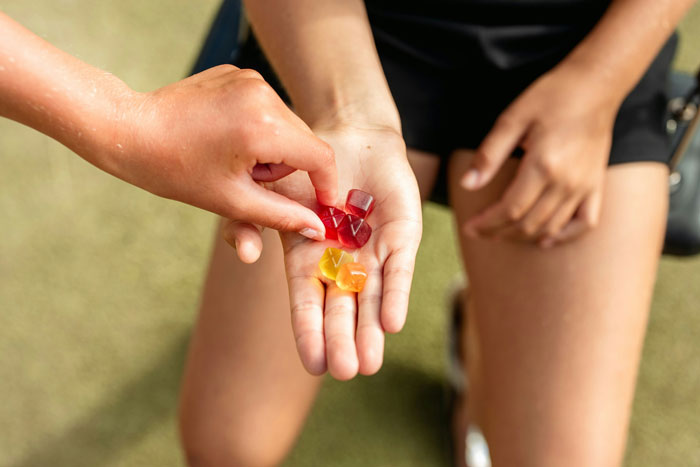 Hands exchanging gummies, illustrating crazy things women do to get a crush to like them.
