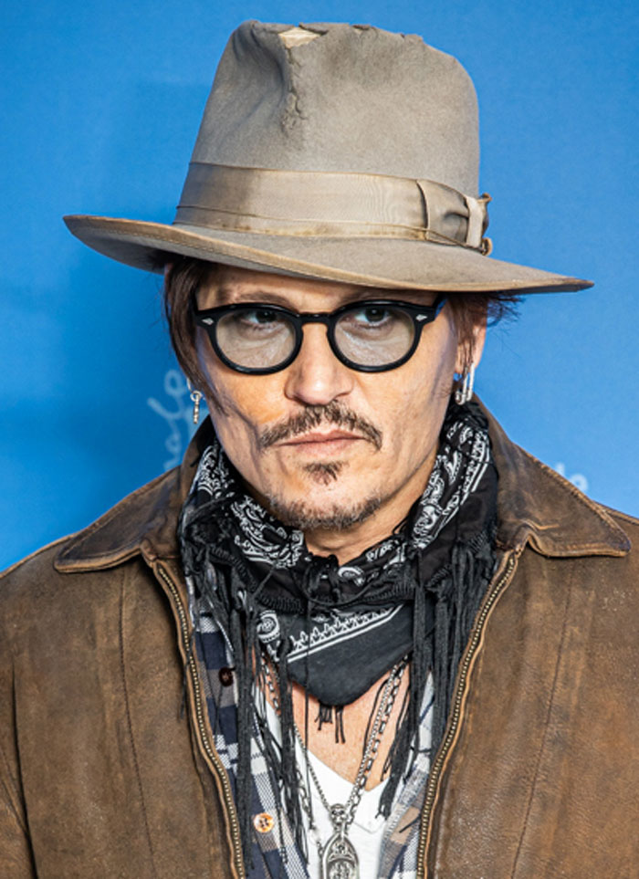 Johnny Depp with a hat, glasses, and a scarf, revealing Hollywood secrets.