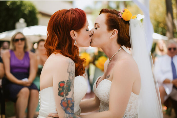 Two brides with red hair kissing during their wedding ceremony