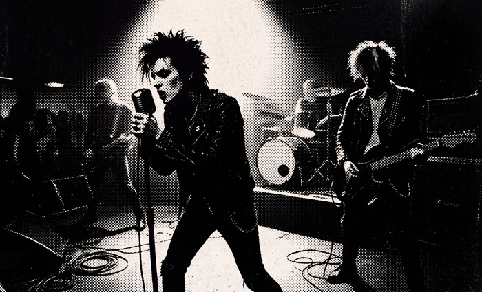 Black and white image of a punk rock band on stage, showing Hollywood secrets.