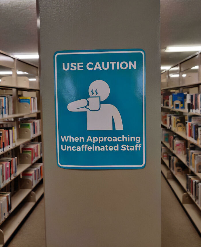 A chaotic sign in a library advises caution when approaching uncaffeinated staff, humorously questioning reality.