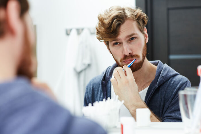 A client brushing their teeth in the mirror, perhaps making a stupid decision.