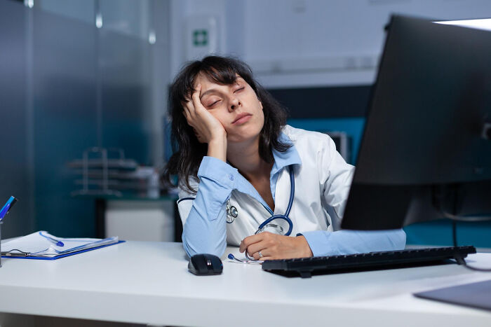 A tired doctor sleeping at a desk, representing the demands of medical procedures and doctors' work.