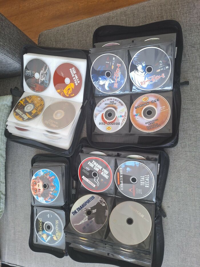 A collection of DVDs and CDs neatly stored in black binder cases, a common sight for retro tech media.