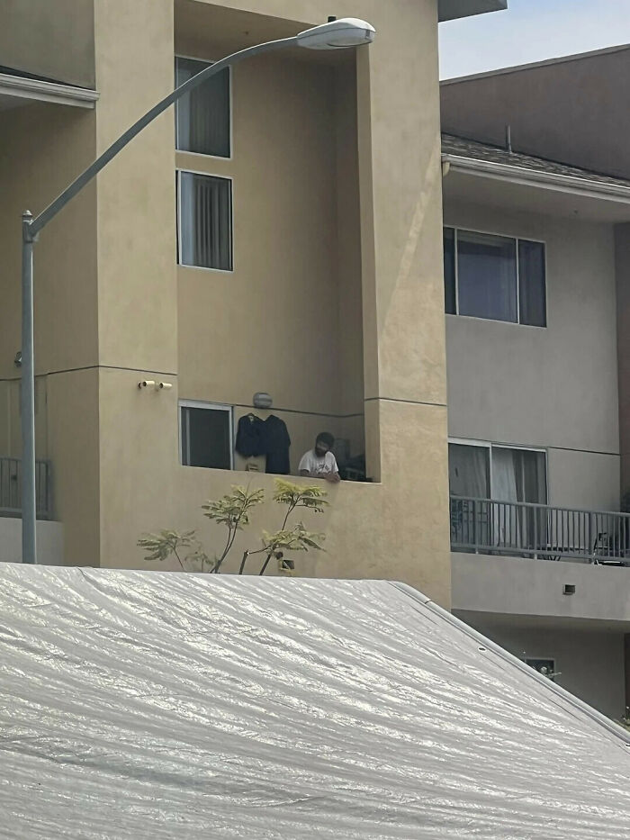 Optical illusion showing a man on a balcony who looks like he is wearing a giant plastic tarp.