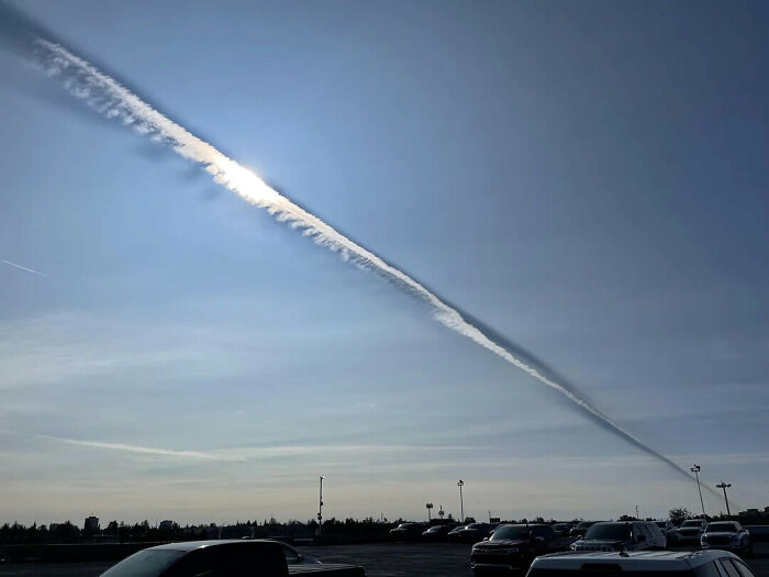 A jet trail in the sky casting a shadow on the clouds, creating a double-take illusion.