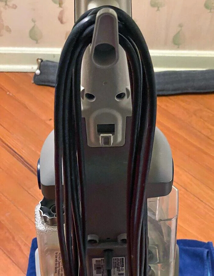 The back of a vacuum cleaner with coiled black cord resembling a surprised face, perfect to look twice.