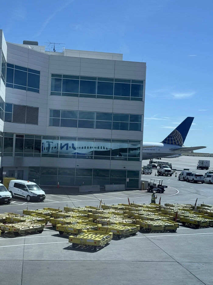Optical illusion showing a plane tail that looks like it is printed on the airport building.