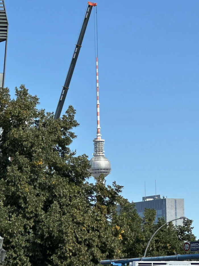Berlin television tower that looks like it is being hoisted by a giant crane in an optical illusion.